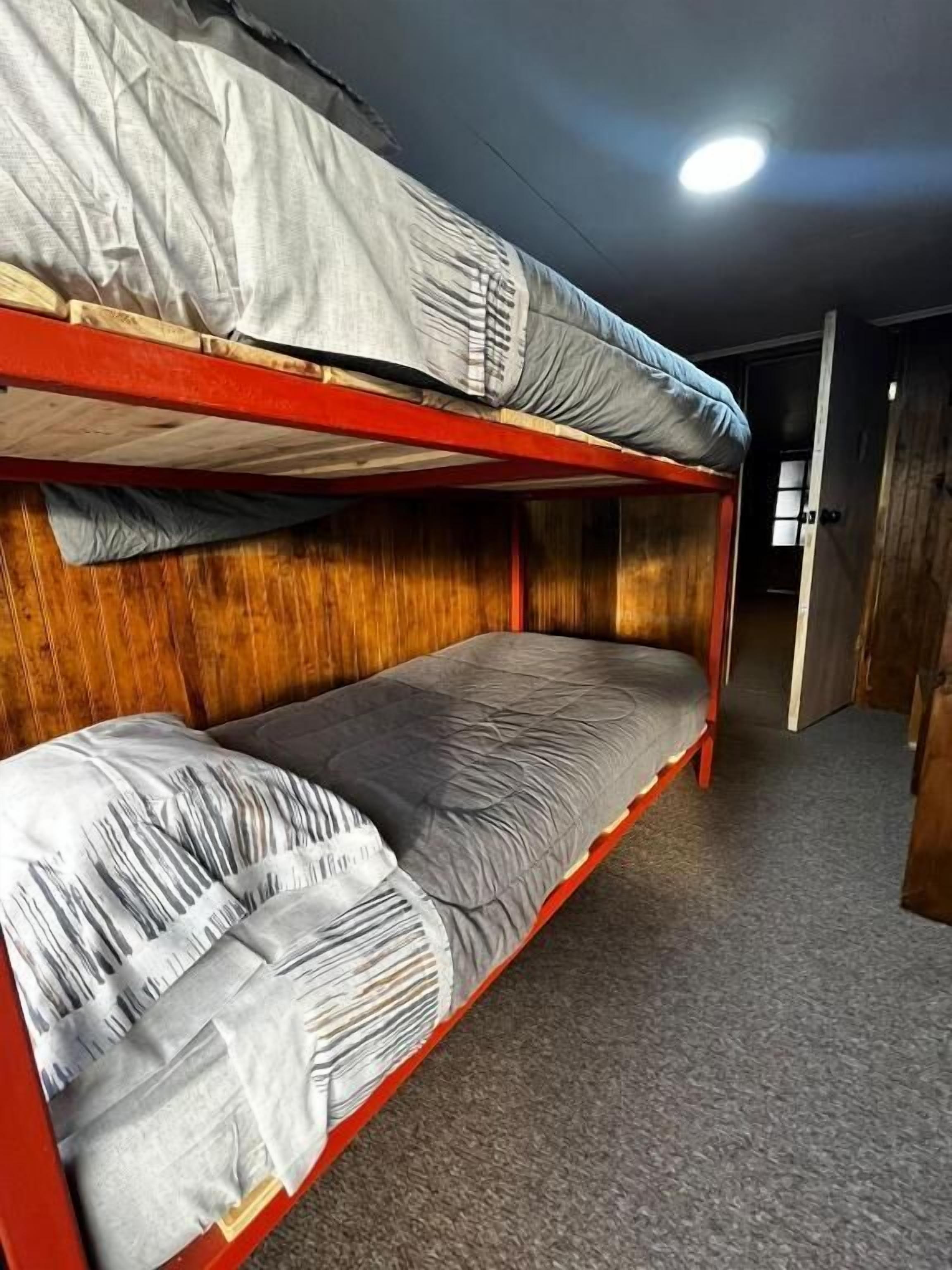 A bunk bed room with wooden walls and a carpeted floor.