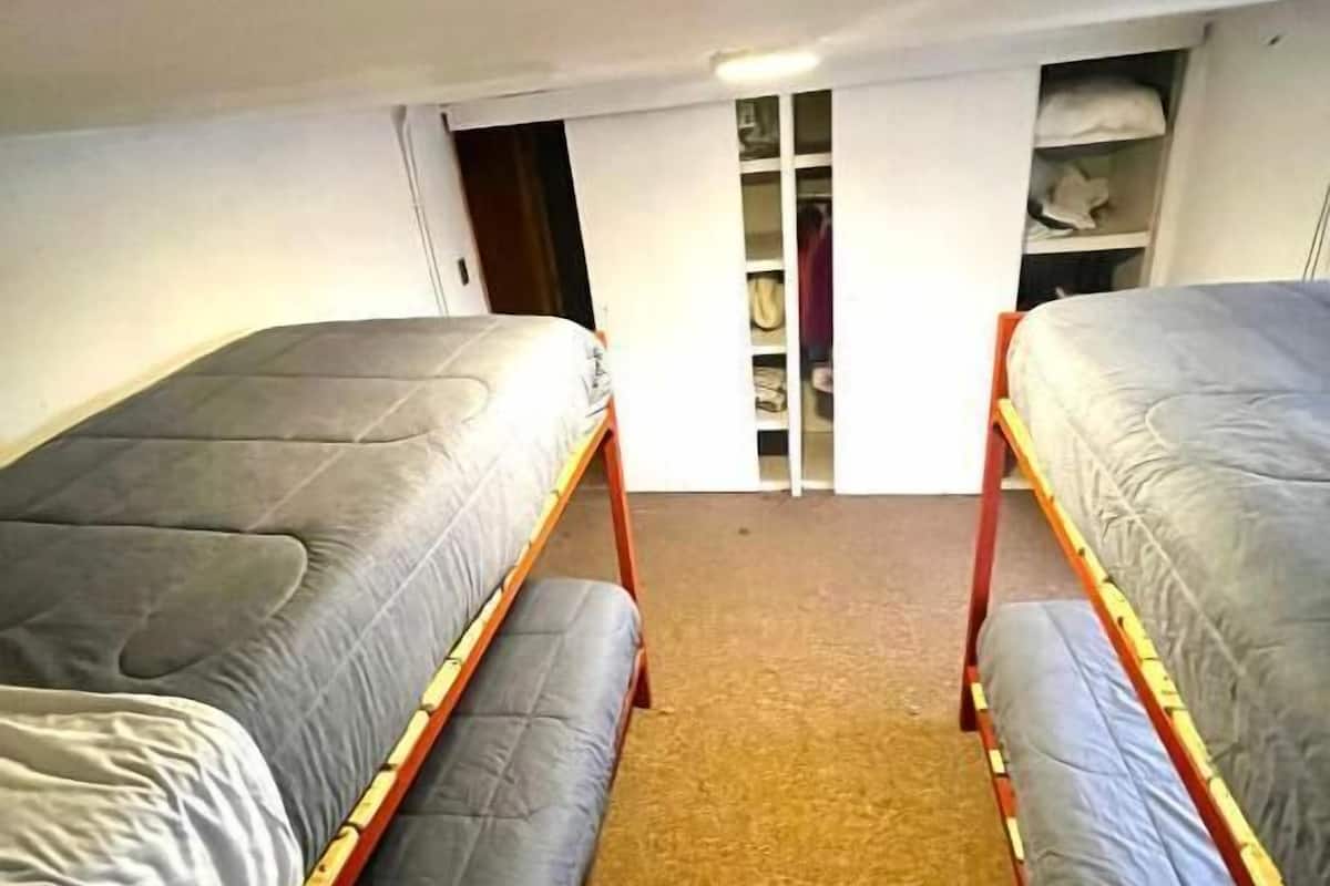 Una habitación con dos literas, un armario con estantes y piso cubierto de alfombra.