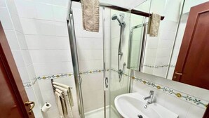 A bathroom with a glass-enclosed shower, a white sink, and a toilet. - Sa Costa 18 (Bosa)