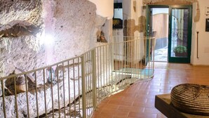 Un intérieur en pierre agrémenté d’une rambarde métallique, d’un sol carrelé et d’une porte donnant sur l’extérieur.
