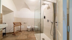 A bathroom with a glass-enclosed shower, a sink, a bidet, and a towel rack. - Sardinian Gallery S'Intrada (Bosa)