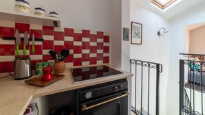 Una cuina amb una salabanc de rajoles vermelles i blanques, una placa de cocció i diversos utensilis de cuina.