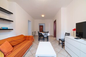 A living room with a sofa, a dining table with chairs, a TV, and a white cabinet. - Sa Costa 33 (Bosa)