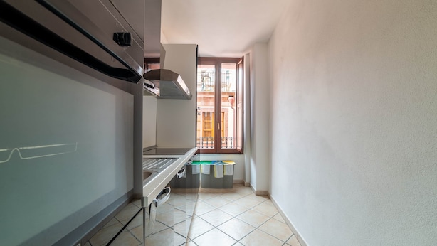 Una cucina con un fornello, una finestra e vista su un balcone.