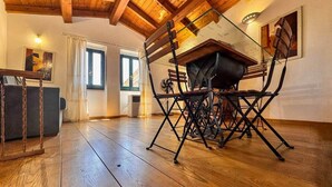 Un comedor con mesa y sillas de madera, un ventilador y una ventana con cortinas.