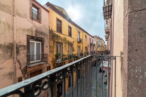 A narrow street with buildings on either side, balconies with railings, and a clear sky. - Sa Piatta 27 (Bosa)