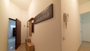 Un passadís amb una obra d'art de paisatge urbà, un telèfon i una banca de fusta.