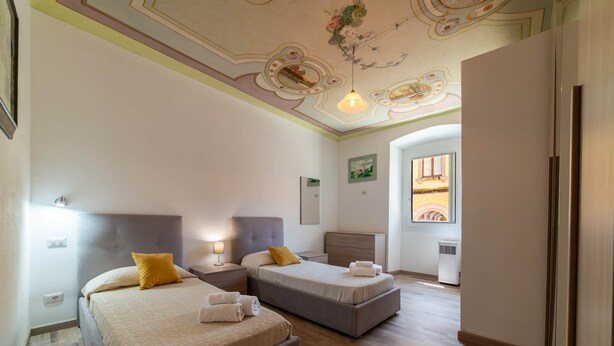 Ein Hotelzimmer mit zwei Betten, einer Decke mit floralem Muster und einem Fenster mit Blick.