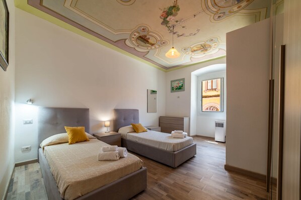 Ein Hotelzimmer mit zwei Betten, einer Decke mit floralem Muster und einem Fenster mit Blick.
