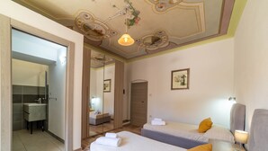 Ein Hotelzimmer mit Bad, Spiegel, Bett mit Kissen und Nachttisch mit Lampe.
