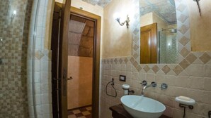 A bathroom with a checkered floor, a large mirror, a sink, and a shower area. - Sardinian Gallery Vittorio (Bosa)