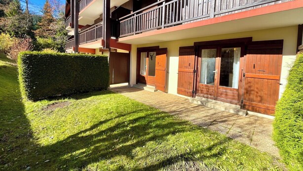 A multi-story residential building with balconies, wooden doors, and a well-maintained lawn. - Bright apartment in Combloux, near ski (Combloux)