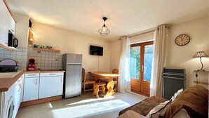 A compact kitchen with a dining area, a washing machine, and a sofa in a bright room with a view through the window. - Bright apartment in Combloux, near ski (Combloux)