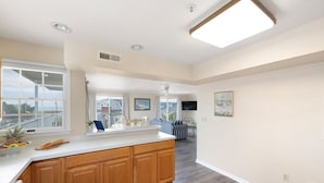A spacious kitchen with a large island, wooden cabinets, and a view of the backyard through the windows. - 70 Steps to the Sand • 2BR/1BA • 2 Balconies • Sleeps 6 (Dewey Beach)
