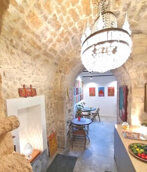 A stone-walled room with a chandelier, a dining area with tables and chairs, and artwork on the walls. - B&B Ibla Art Centro Ragusa (Ragusa)