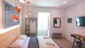 A modern bedroom with a large bed, a desk, and a television. - B&B Ibla Art Centro Ragusa (Ragusa)