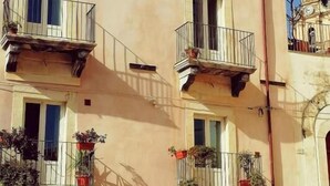 A multi-story building with balconies, potted plants, and a small entrance door. - B&B Ibla Art Centro Ragusa (Ragusa)