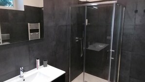 A modern bathroom with a glass-enclosed shower, a white sink, and a dark-toned vanity. - B&B Ibla Art Centro Ragusa (Ragusa)