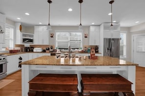 A kitchen with white cabinets, a granite countertop, a stainless steel refrigerator, and a double sink. - 6 Bedrooms | Bar Lounge & Pool | Foosball (Wetumpka)