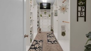 A hallway with white walls, a mounted TV, a decorative wall clock, and a 'HPE' sign.