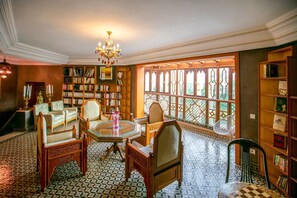 Eine Bibliothek mit einem großen Fenster, Bücherregalen und einer Chandelier.