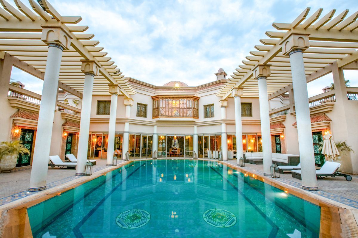A pool area with a central pool, surrounded by lounge chairs and a covered seating area.