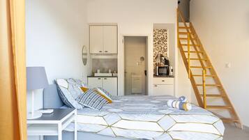 A bedroom with a bed, a desk, a wardrobe, a bathroom, and a wooden staircase.