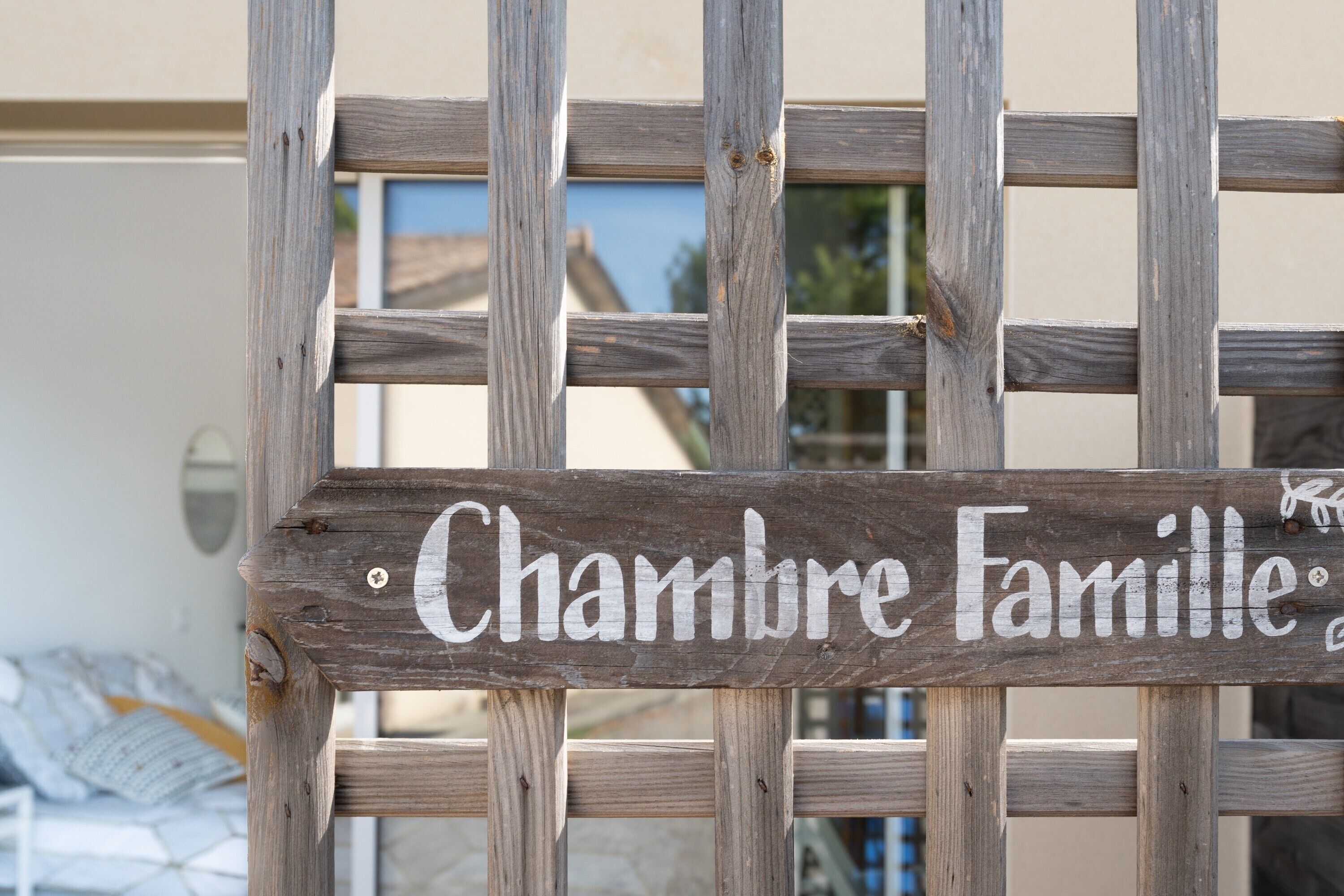 Une enseigne en bois portant l’inscription « Chambre familiale » est fixée sur une structure en treillis.