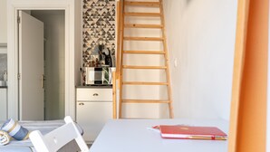 Une pièce avec une table blanche, un carnet rouge, une échelle en bois et un mur à motifs.