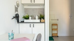 A compact kitchen with white cabinets, a countertop, a hairdryer, a mirror, and a small potted plant. - “Nature Room” Guesthouse with Shared Terrace, Wi-Fi, and Air Conditioning (Saint-Savin)