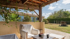An outdoor patio with a covered seating area, a table with a mug and a bowl, and a view of a house in the background. - “Nature Room” Guesthouse with Shared Terrace, Wi-Fi, and Air Conditioning (Saint-Savin)