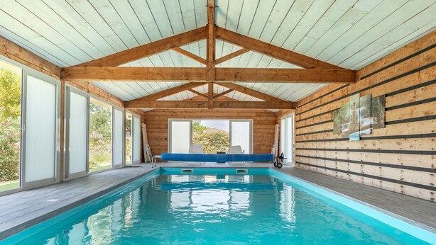An indoor swimming pool with wooden beams, large windows, and a bench. - “Nature Room” Guesthouse with Shared Terrace, Wi-Fi, and Air Conditioning (Saint-Savin)