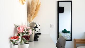 A white table with potted plants, a coffee maker, and a mirror.