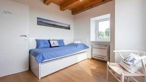 Una camera da letto con un letto, una finestra, un termosifone e una porta.