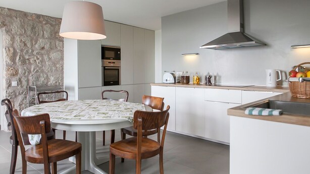 Una cucina moderna con un'isola centrale, forni integrati e una parete decorativa in pietra.