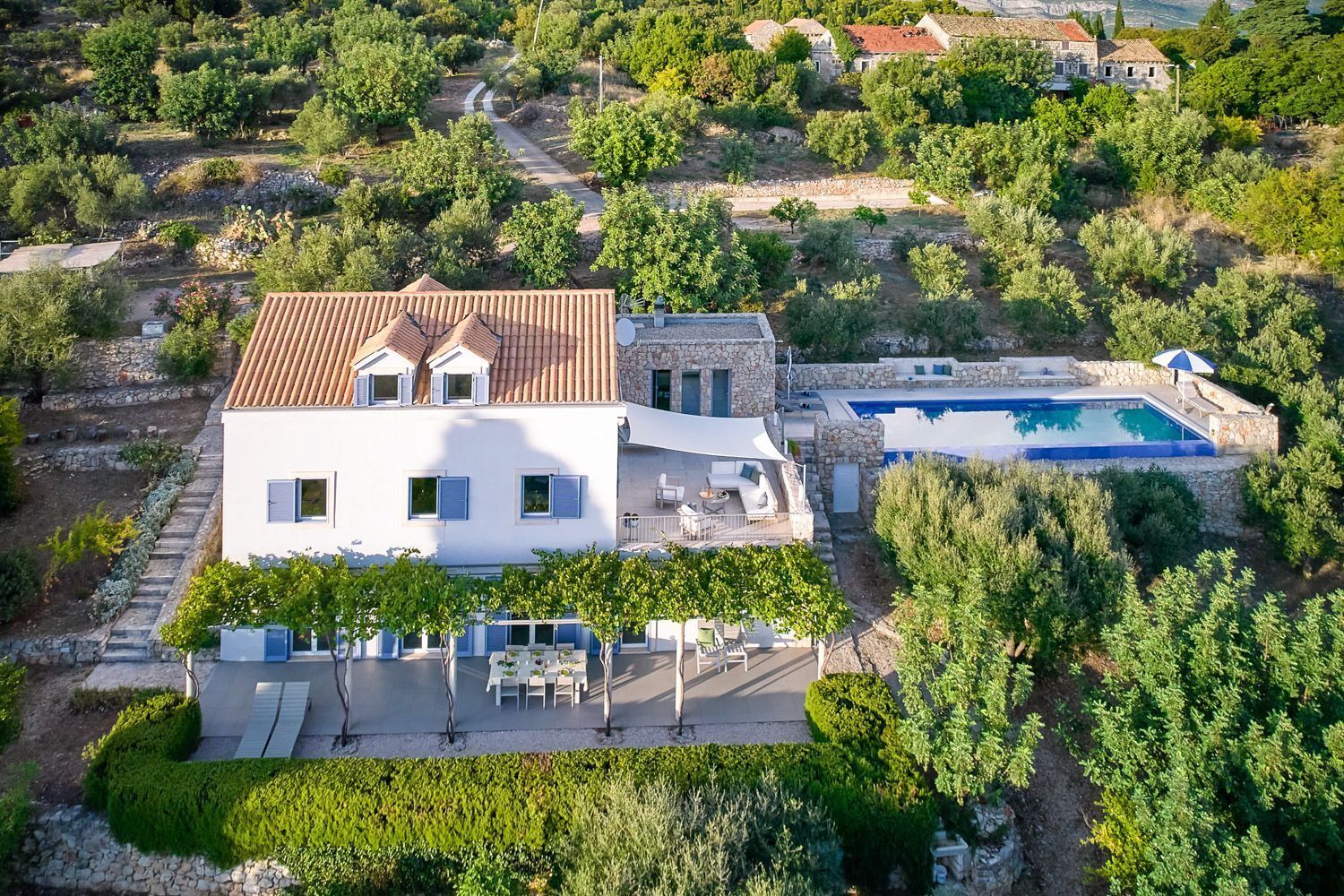 Une grande villa dotée d’une piscine, de murs en pierre et d’un jardin.