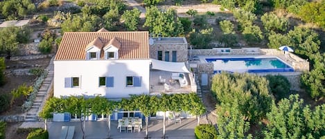 Una amplia villa con piscina, muros de piedra y jardín.