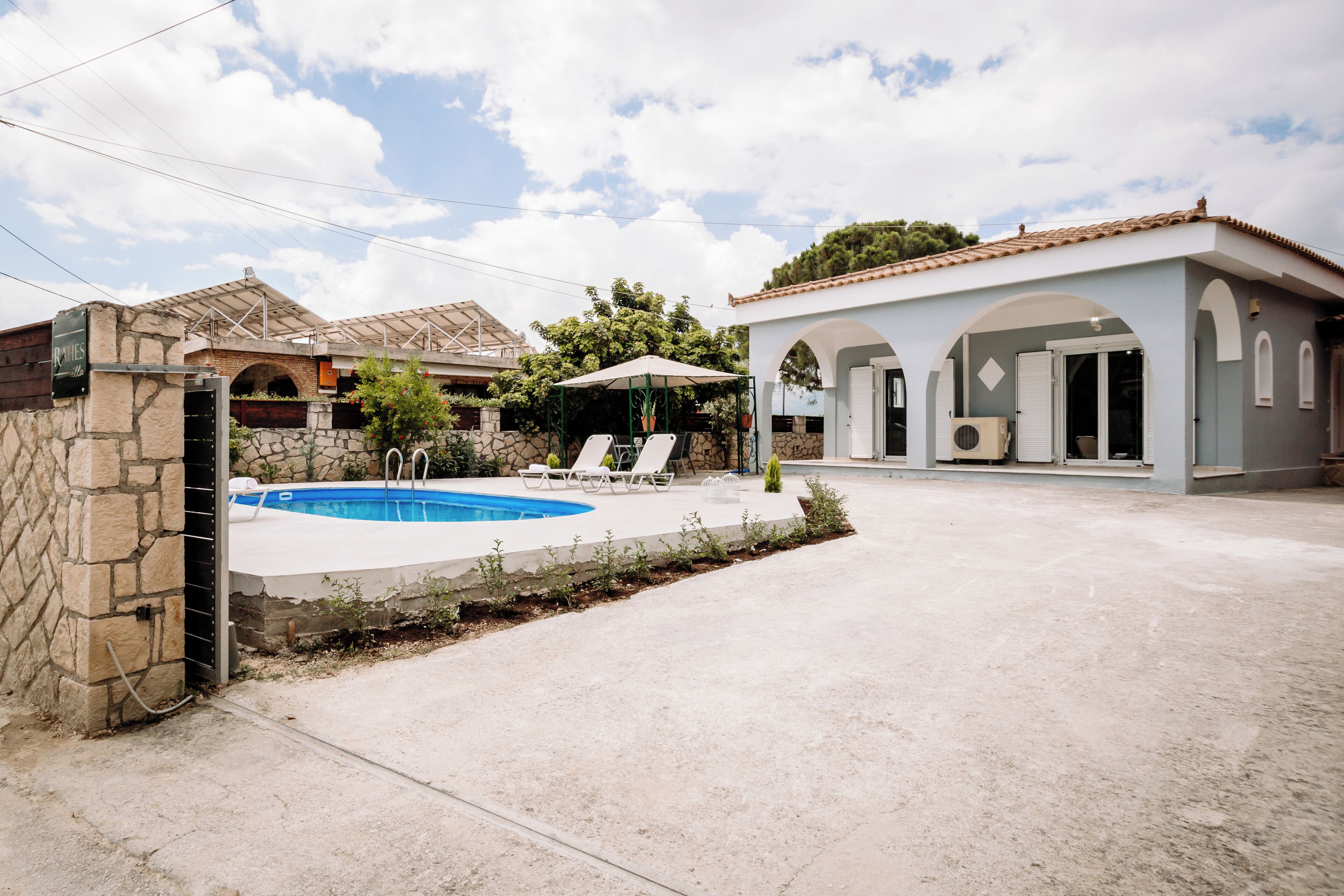 A residential property with a swimming pool, stone walls, and a covered patio area.