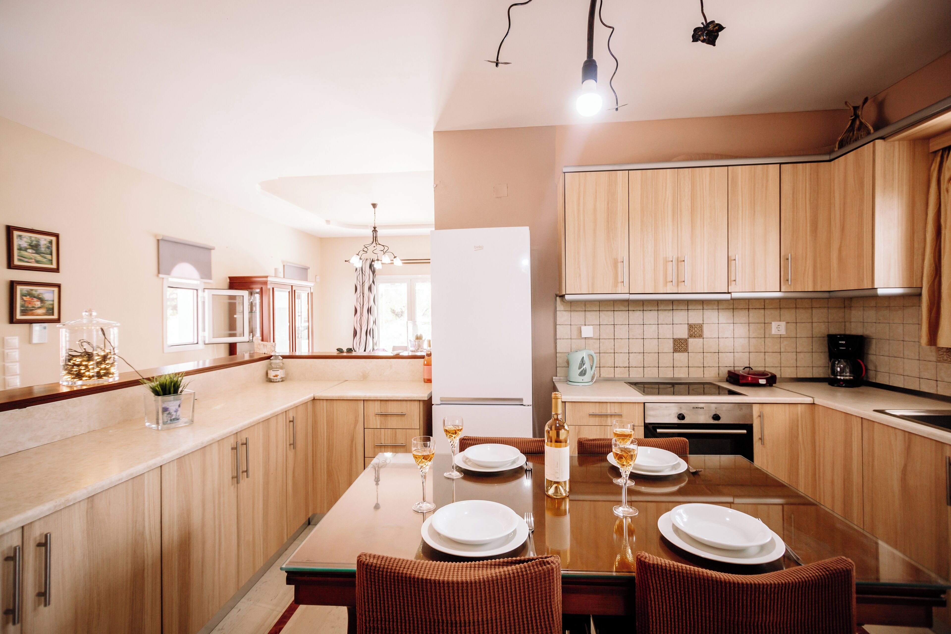 A modern kitchen with wooden cabinets, a central island with seating, and a dining table set for four.