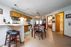 A kitchen with wooden cabinets, a microwave, and a refrigerator. There is a dining area with a table and chairs. - Innsbrook Vacation Condo 30 (Ruidoso)