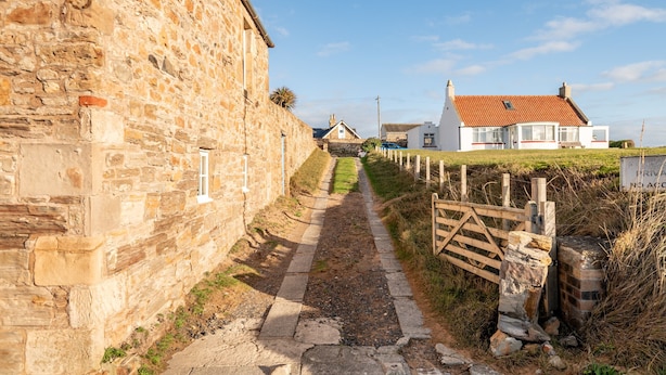 Un étroit sentier de pierres mène à un bâtiment traditionnel en pierre sur lequel est apposée une enseigne indiquant « THE TOFT ».