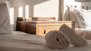 Un lit bien fait, avec des draps blancs et une serviette enroulée posée sur le côté.