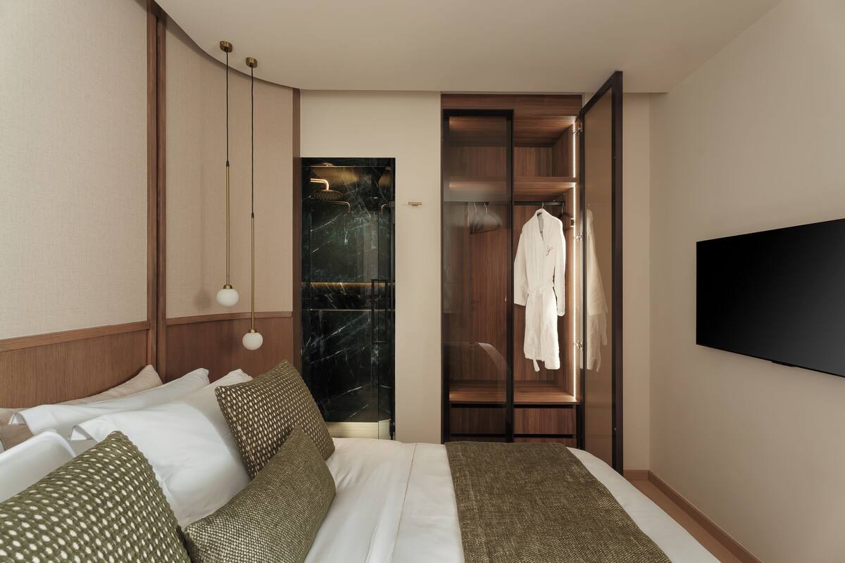 A modern hotel room with a bed, a wardrobe, and a television.