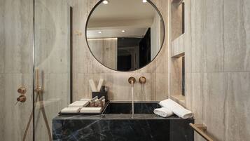 A modern bathroom with a marble sink, a round mirror, and a towel rack.
