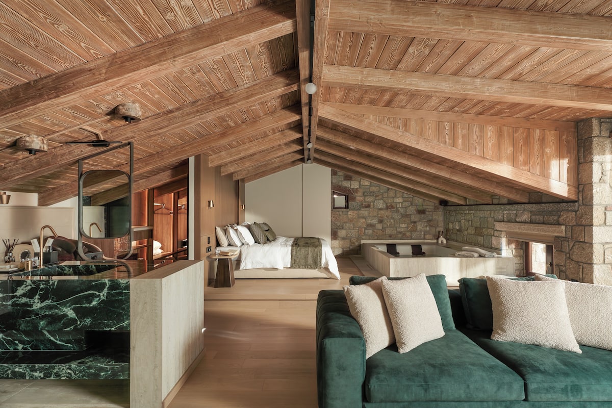 A spacious loft with a high ceiling, a stone fireplace, a green sofa, and a marble kitchen island.