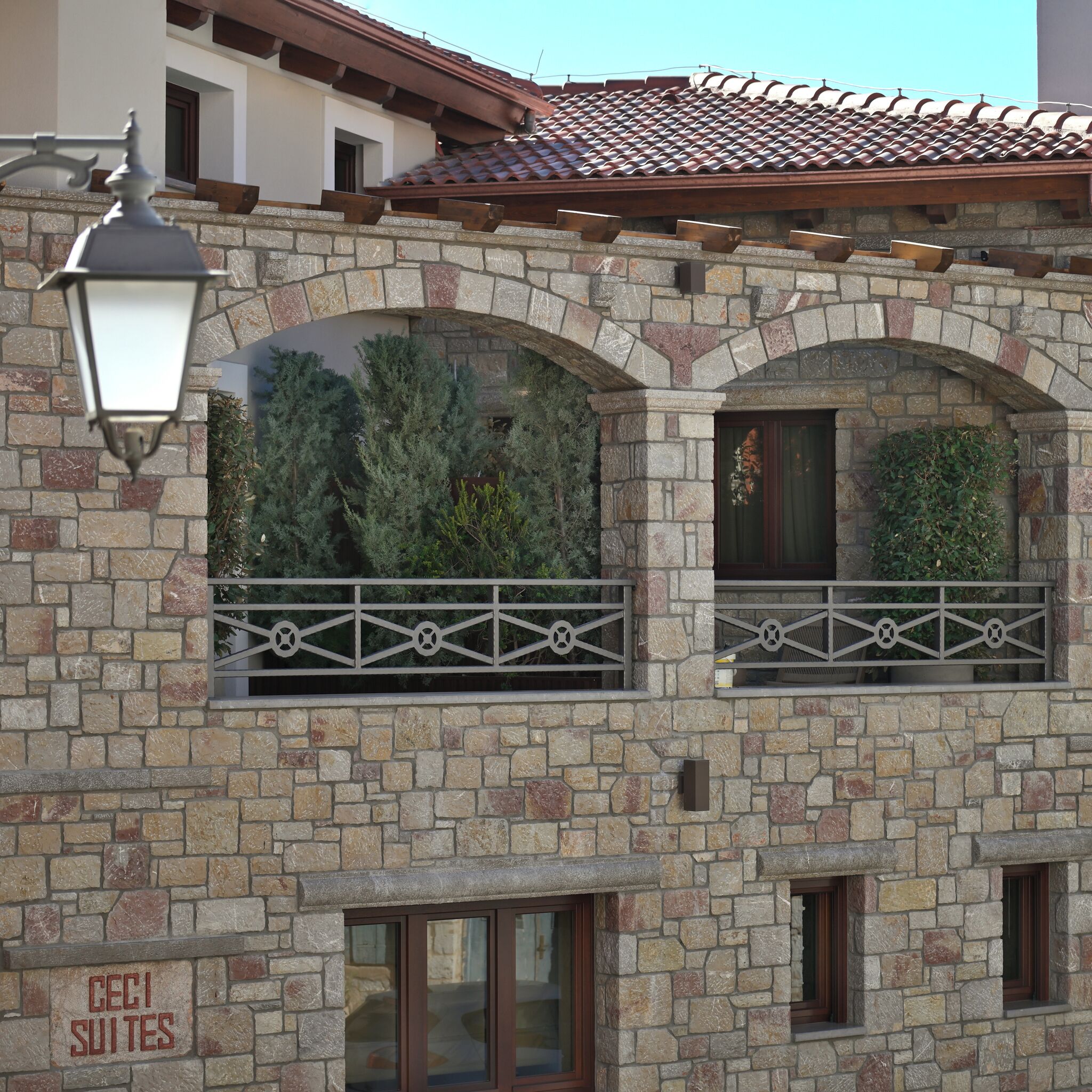 Un edificio de piedra con ventanas de arco, un cartel que dice "CECI SUITES" y una barandilla de metal.