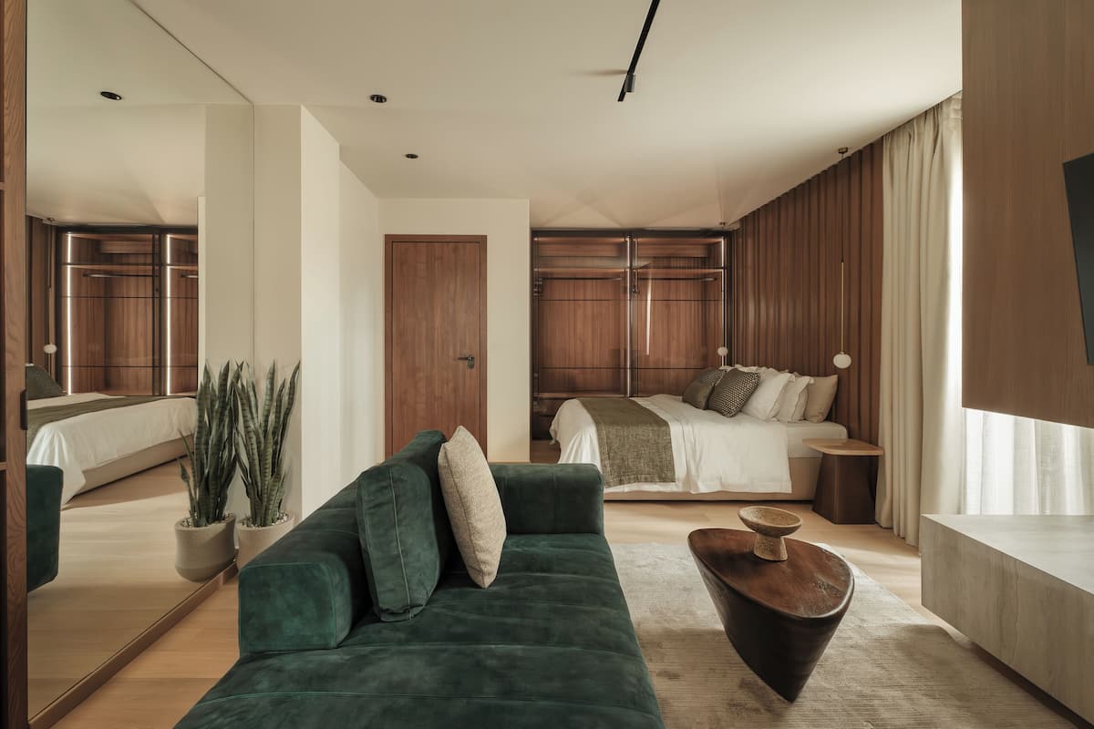 A modern bedroom with a large bed, a green sofa, and wooden cabinets.