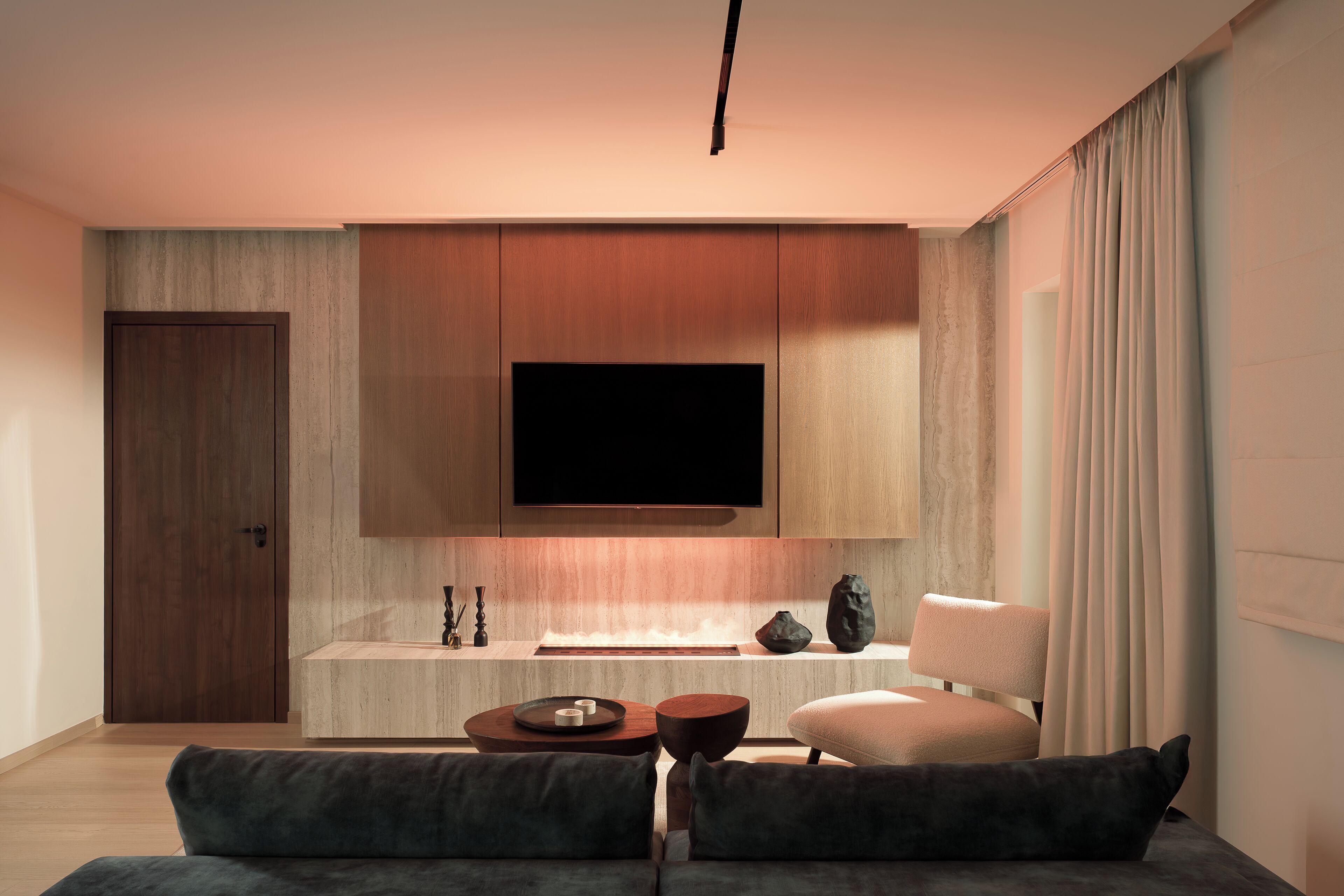 Una sala moderna con un televisor de pantalla plana sobre un mueble de madera, un sofá con cojines, una mesa de centro y una silla.