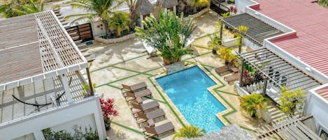 Un resort con piscina, sillones de descanso y plantas tropicales.