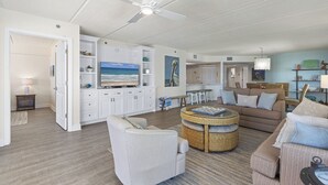 Ein geräumiges Wohnzimmer mit Deckenventilator, einem großen Fernseher und einem Essbereich mit Tisch und Stühlen.